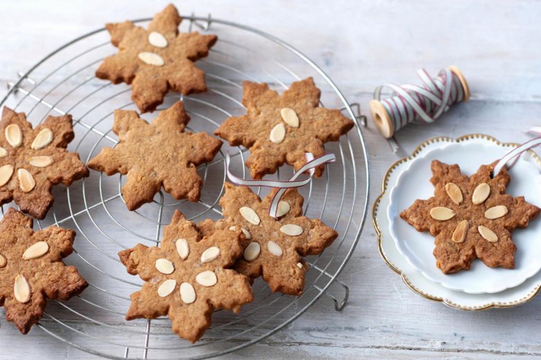 Speculaas biscuits cooling on a wired-rack with a reel of thread ready to hang on a Christmas tree.