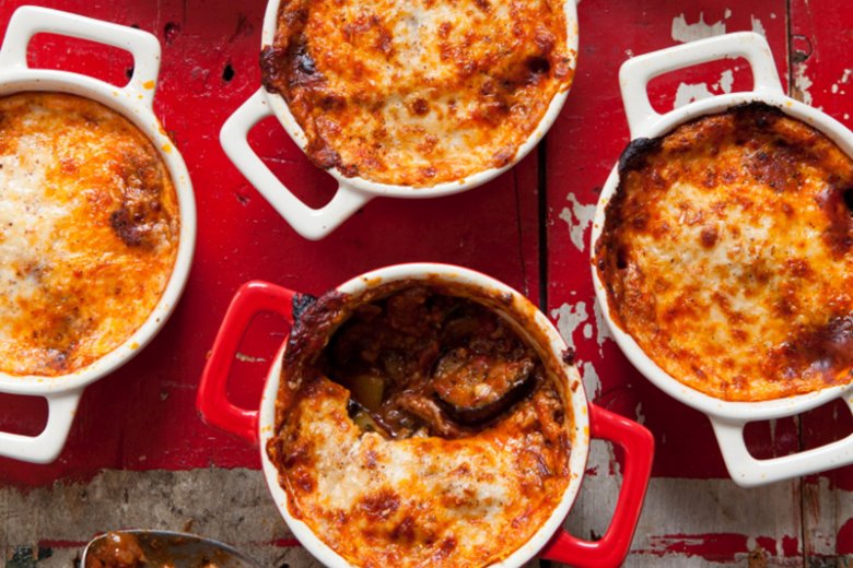 Four casseroles with Hairy Dieters' Moussaka with meat and cheese on a red table cloth.