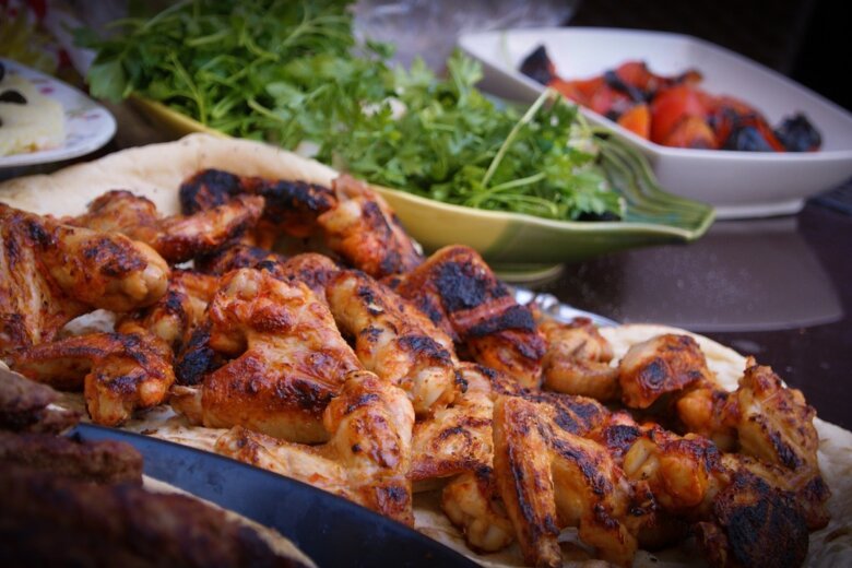 Grilled jerk chicken pieces on flatbread, accompanied by fresh herbs and a bowl of a vibrant vegetable dish, inspired by the Hairy Dieters Eat For Life recipe.