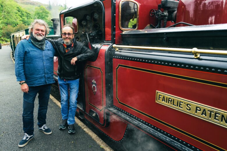 Si KIng and Dave Myers at the standing by a red train at the Ffestiniog Railway in North Wales