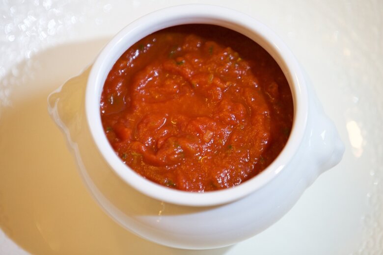 A white bowl filled with rich, red tomato sauce sits on a pristine white surface, reminiscent of a Hairy Bikers recipe by Si King using fresh passata.