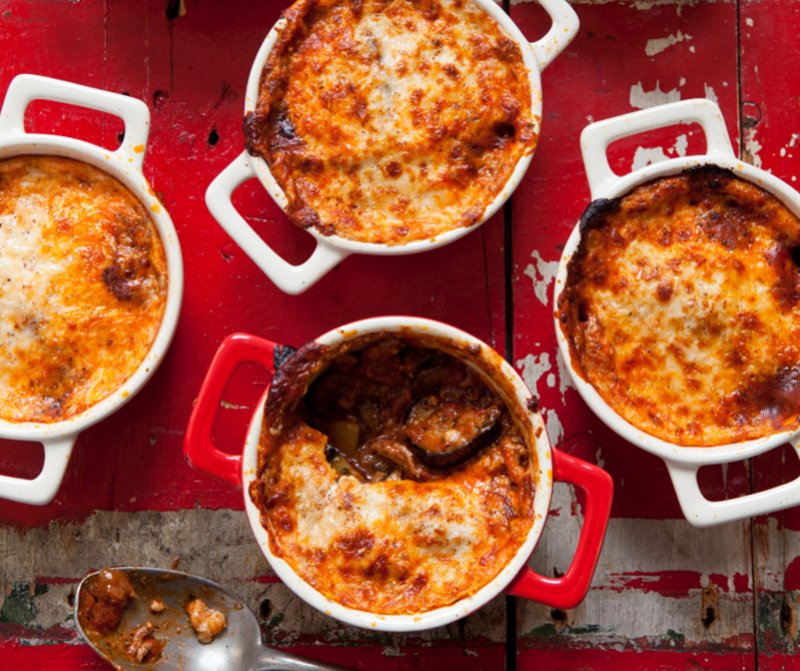 Four casseroles with Hairy Dieters' Moussaka with meat and cheese on a red table cloth.