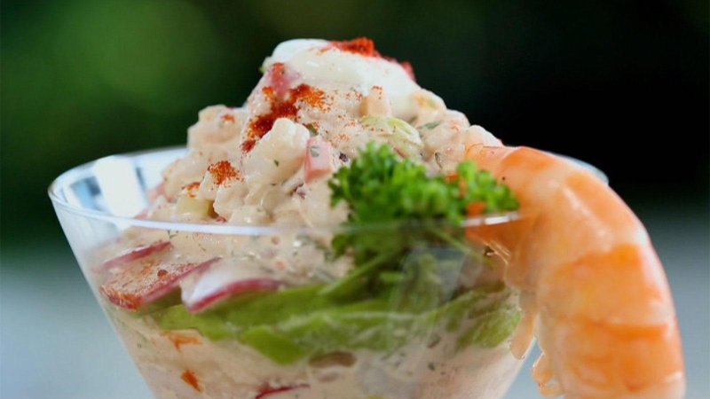 A prawn cocktail served in a glass dish with a prawn placed on the edge pointing down.